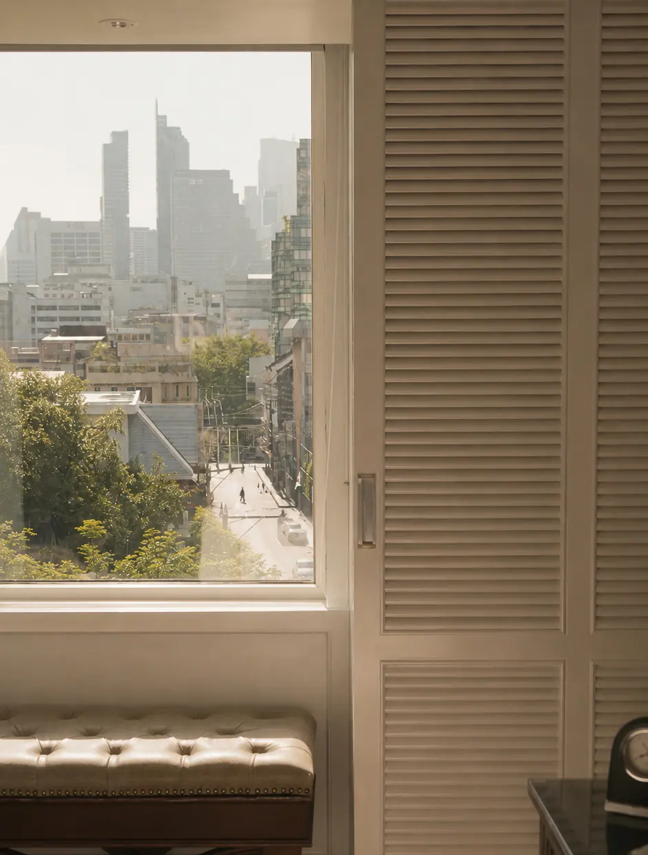 City skyline seen through a window beside louvred shutters