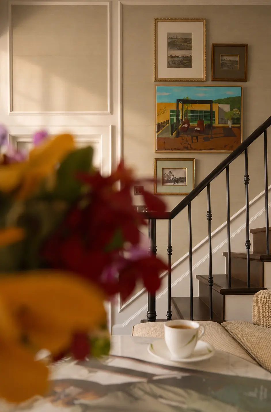 Sunlit interior with flowers, a staircase and framed pictures